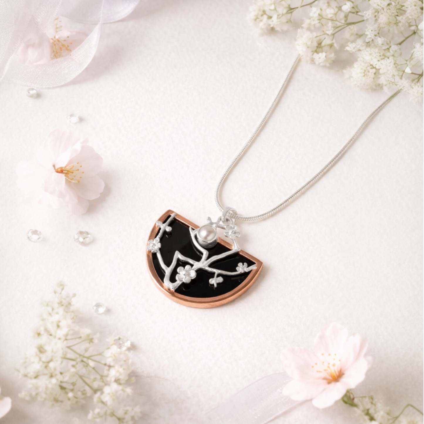 Cherry blossom Necklace with a black and rose gold pendant on a white background with flowers.