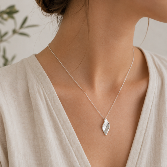 Woman wearing sculpted leaf sterling silver pendant necklace inspired by flowing botanical forms and organic movement