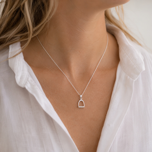 Model wearing a small sterling silver stirrup pendant necklace inspired by equestrian style