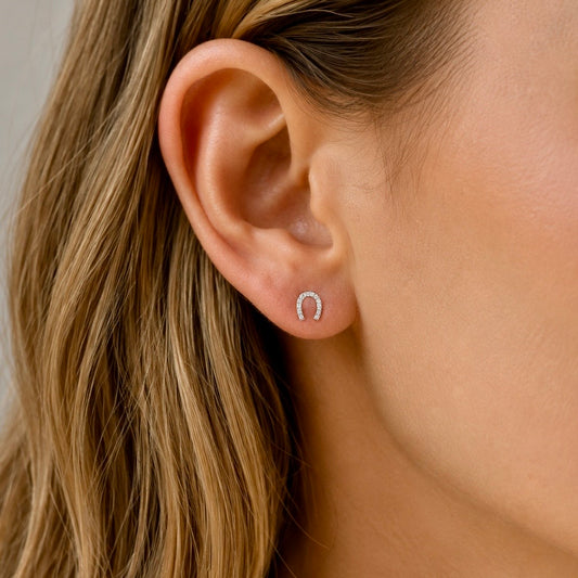 Woman wearing sterling silver horseshoe stud earrings set with cubic zirconia stones