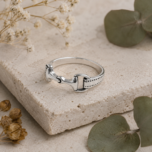 Sterling silver snaffle ring displayed on a limestone stone and botanical flat lay background.