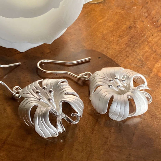 Picture showing our handmade sterling silver oriental Lily earrings displayed on a antique jewellery box from twelve silver trees jewellery and gifts 