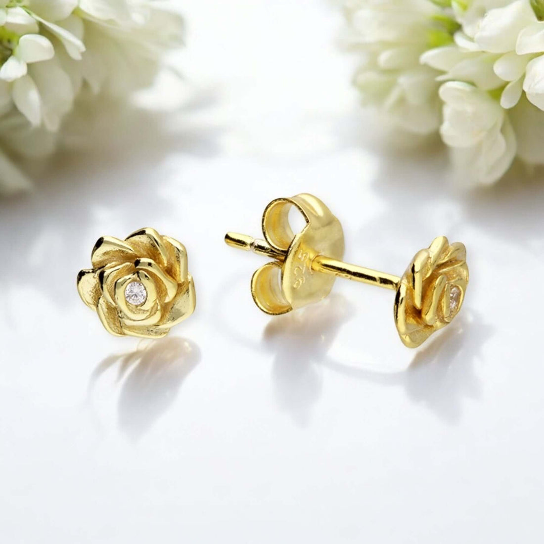 Image of dainty sterling silver and 18 carat gold rose flower stud earrings on a simple and minimal floral background 
