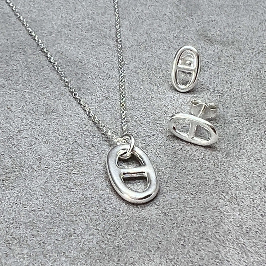 Hidden Symbolism - The Anchor Link Charm In Jewellery blog post cover image featuring a sterling silver mariner link pendant and earrings on a grey suede background from twelve silver trees jewellery and gifts