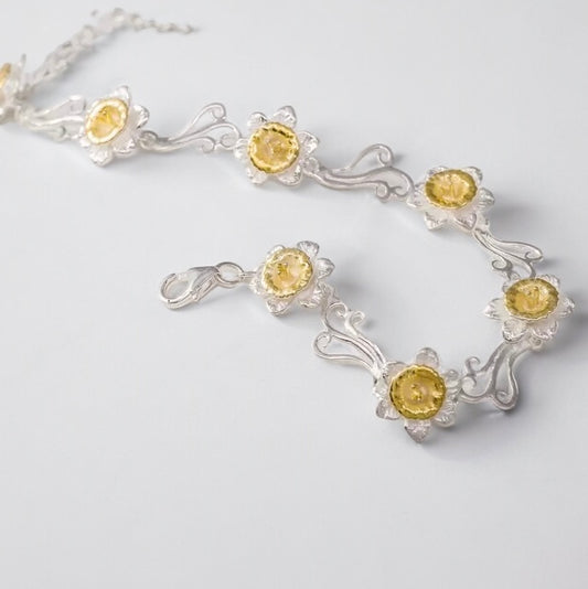 Handmade daffodil bracelet with foliage inspired links made in sterling silver with 14 carat gold details. Available from Twelve Silver Trees Jewellery and gifts. 