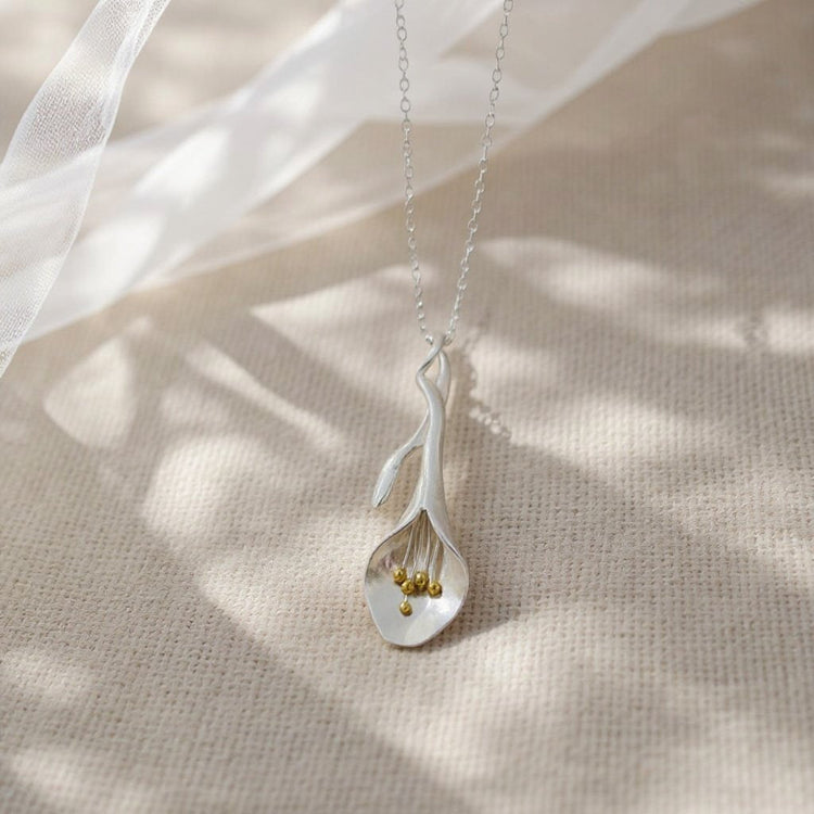 Image of our handmade sterling and 18 carat gold Lily pendsnt on a velvet background 