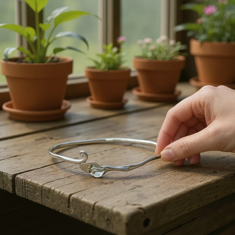 Image of a handmade sterling silver bangle with 18 carat gold accents set with with a blue opal solitaire gemstone 
