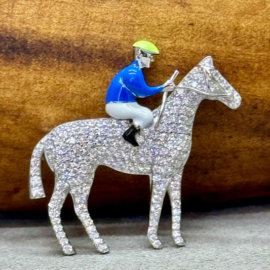 Stunning antique inspired hand crafted sterling silver brooch of a horse & jockey. The horse is covered in pave-set high carbon zirconia gemstones while the jockey is enamelled in blue and white. 