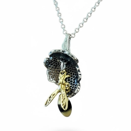 Handmade sterling silver bee pendant with baltic Amber bodies and gold plated wings suspended from concave honeycomb in pierced silver from the bee collection at Twelve Silver Trees Jewellery 