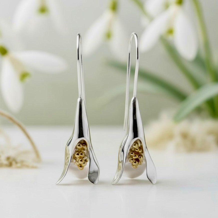 Handmade sterling silver and gold stylised snowdrop earrings on subtle, diffused background 