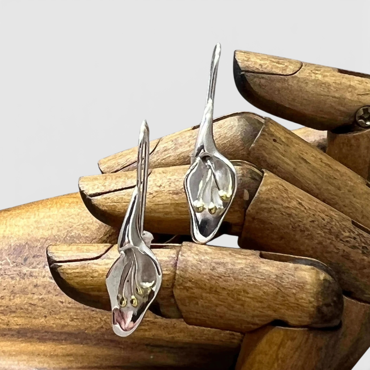 Sterling Silver calla lily flower earrings earrings on a wooden hand from the herbarium collection at Twelve Silver Trees Jewellery 