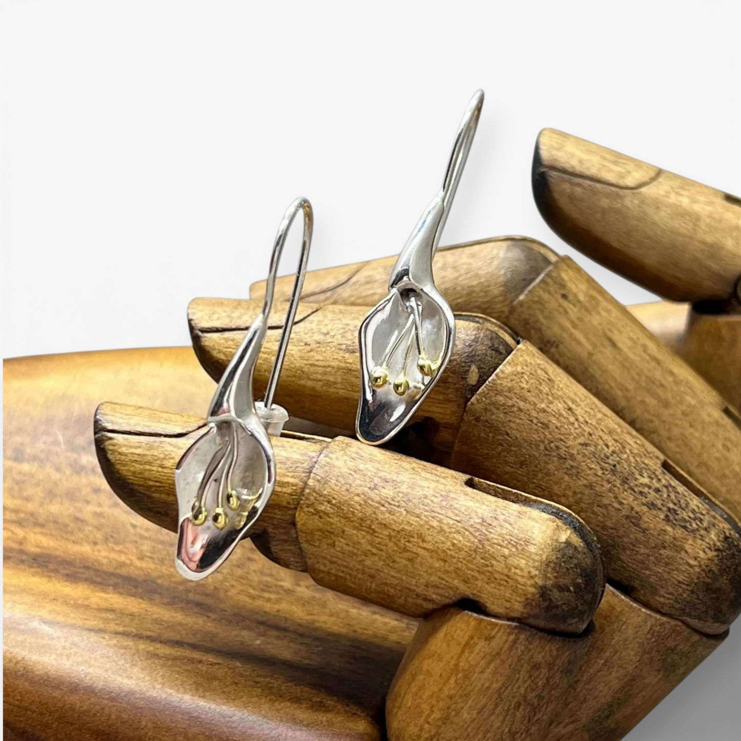 Handmade sterling Silver Calla lily earrings on a wooden hand model from the herbarium collection at Twelve Silver Trees Jewellery 