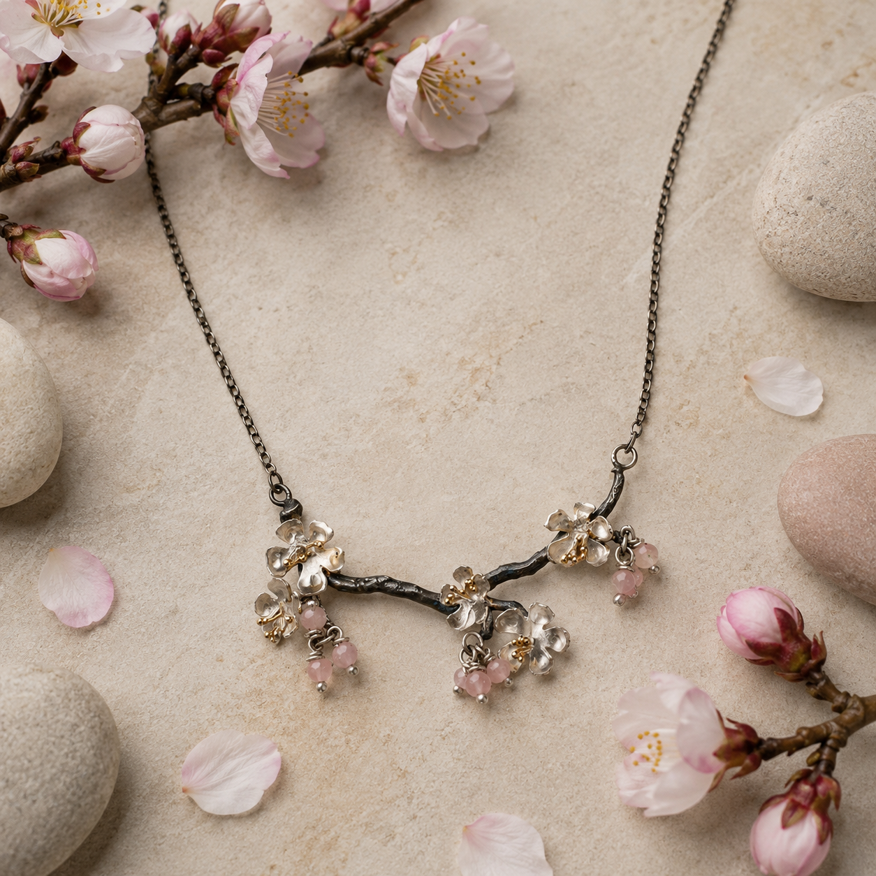 Almond Blossom branch necklace with blossom flowers and pink gemstone accents displayed on a botanical flatlay
