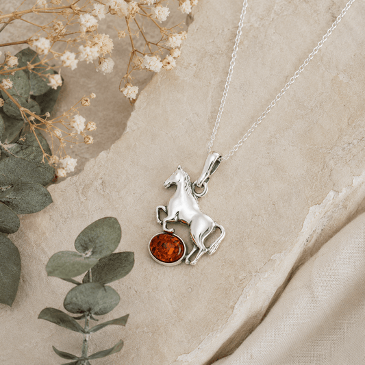 Sterling silver horse pendant necklace with amber gemstone styled on natural stone with eucalyptus and dried flowers