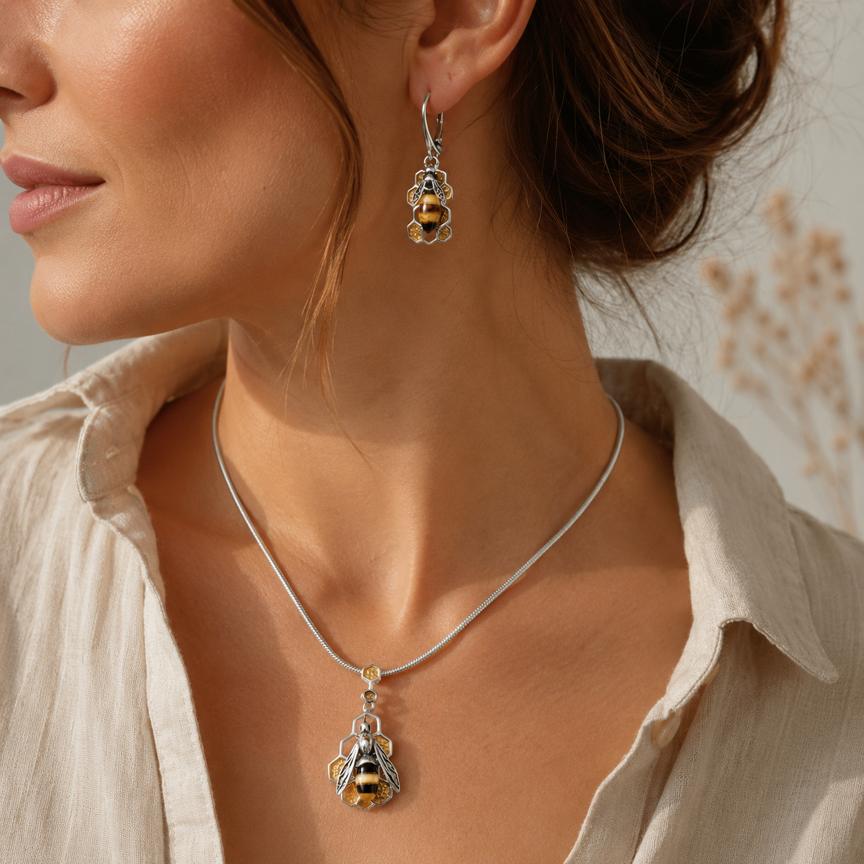 Woman wearing sterling silver Baltic amber bee and honeycomb earrings with matching pendant necklace