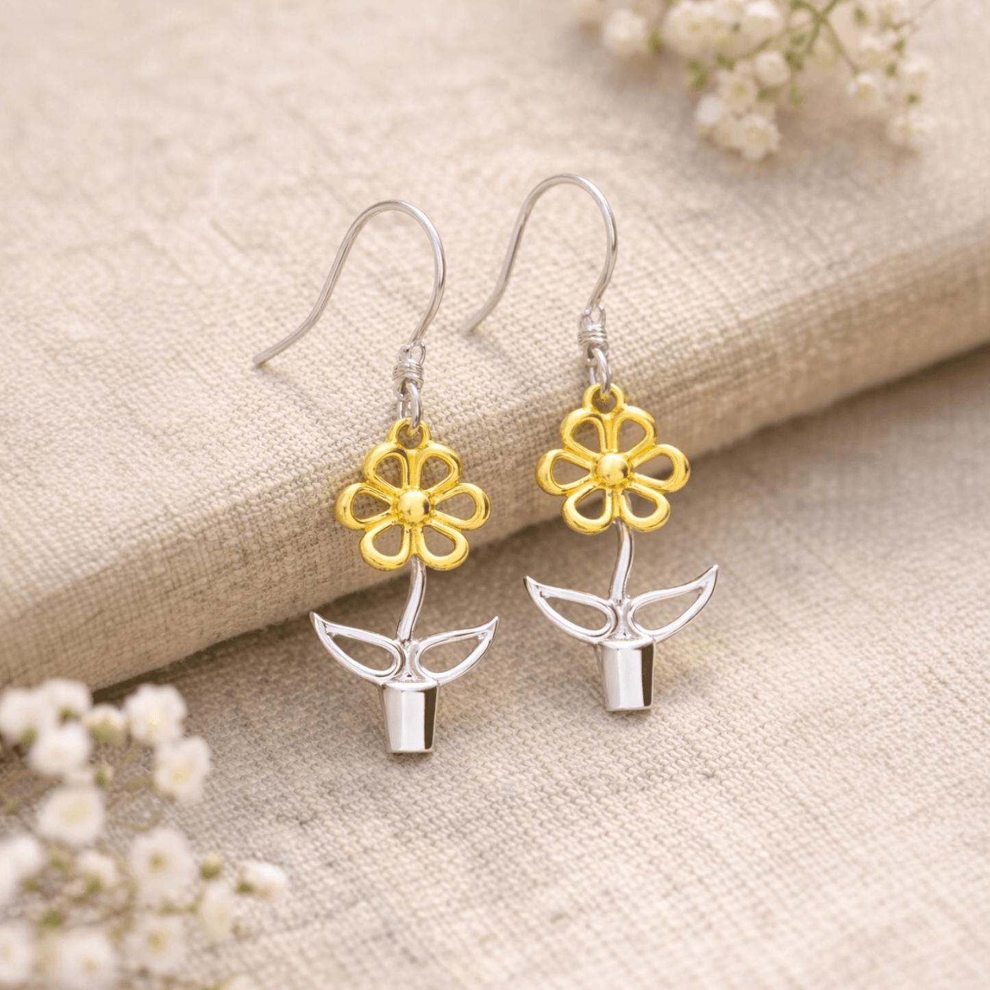 Sterling silver and gold Blooming Joy flower pot earrings styled on natural linen with soft botanical details