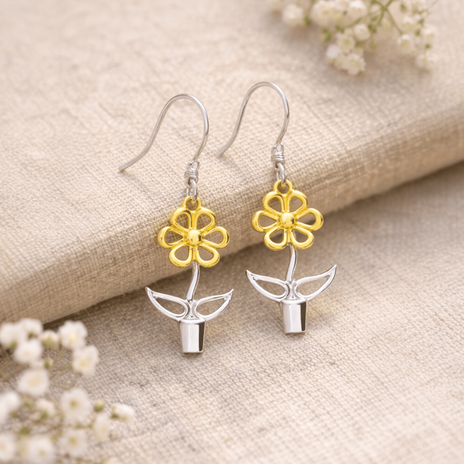Sterling silver and gold Blooming Joy flower pot earrings styled on natural linen with soft botanical details
