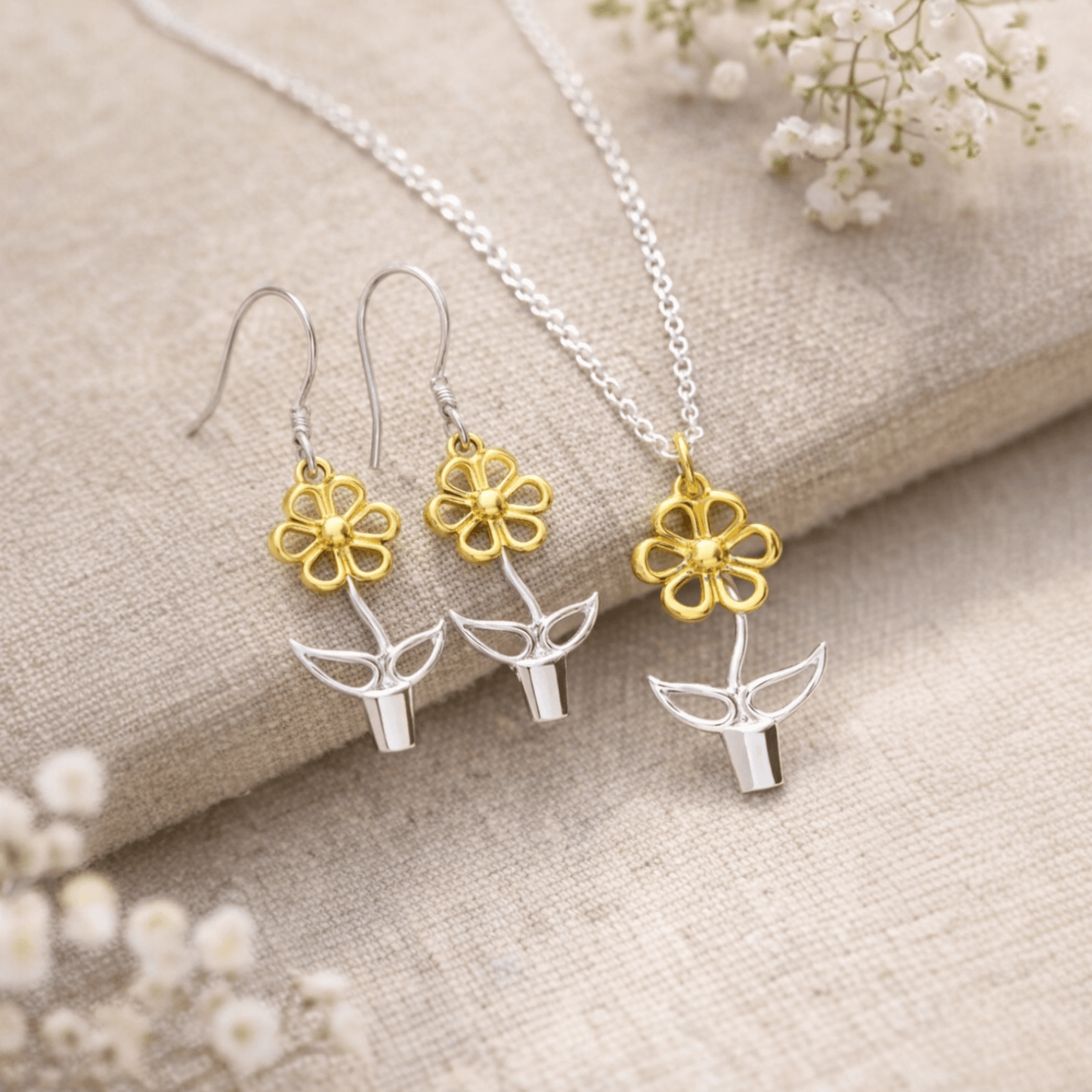 Blooming Joy flower pot pendant necklace and matching earrings in sterling silver and gold styled on stone with botanical accents