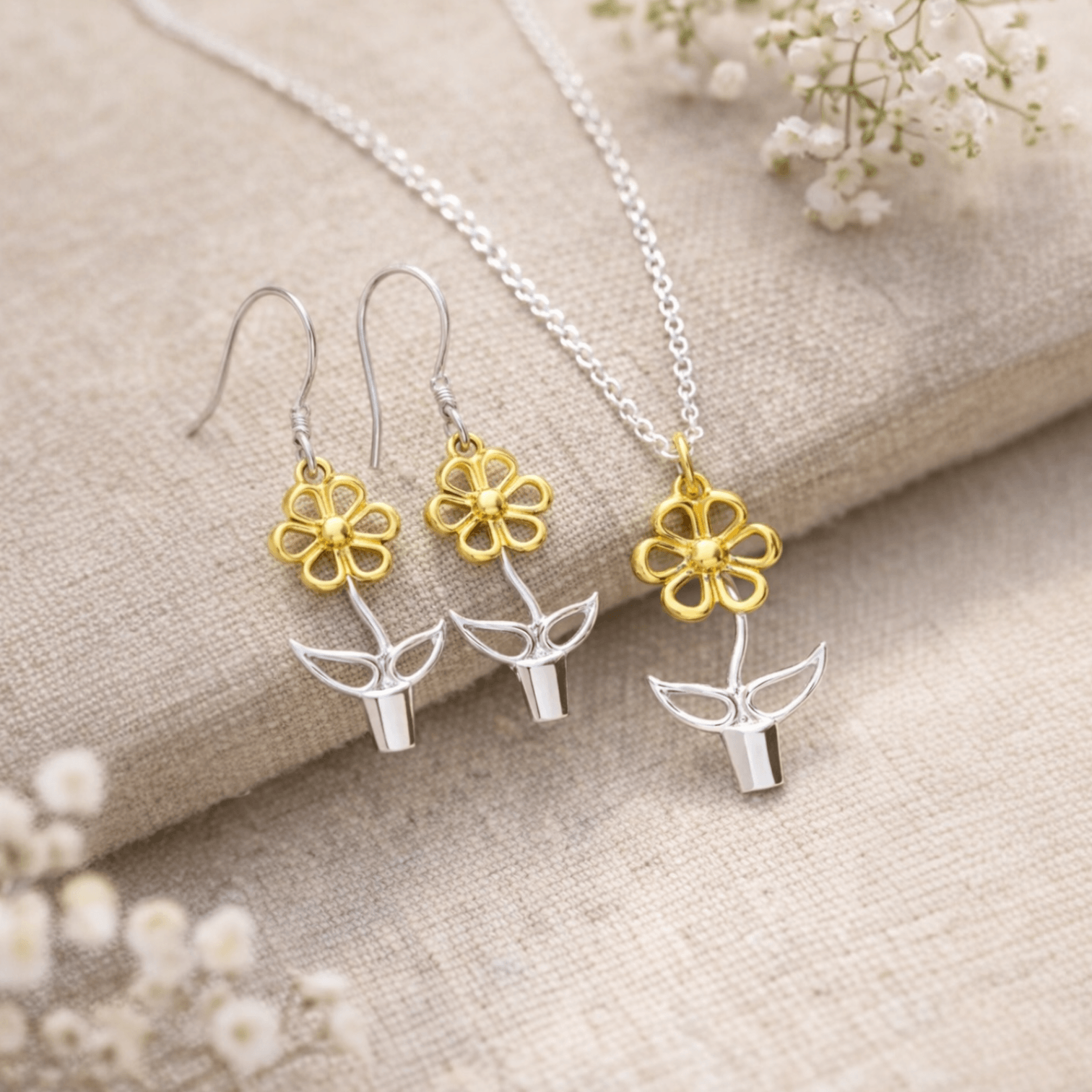 Blooming Joy flower pot pendant necklace and matching earrings in sterling silver and gold styled on natural linen