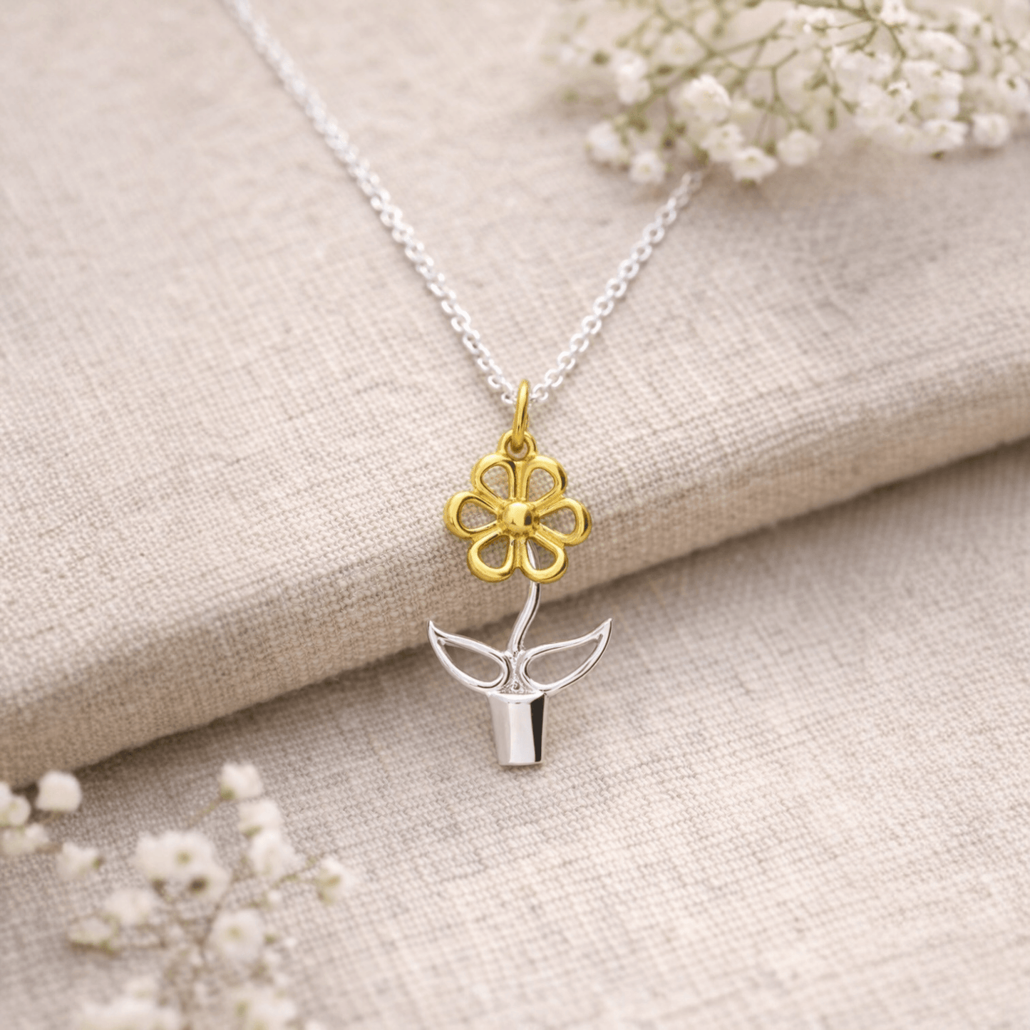 Sterling silver and gold Blooming Joy flower pot pendant necklace styled on natural linen with delicate botanical details