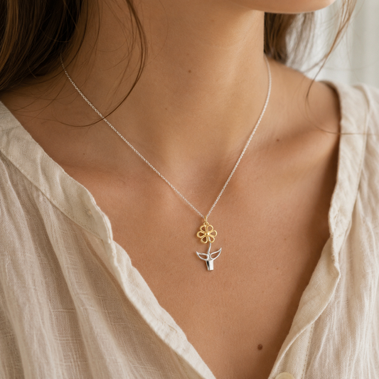 Woman wearing the Blooming Joy flower pot pendant necklace in sterling silver and gold with soft natural linen styling