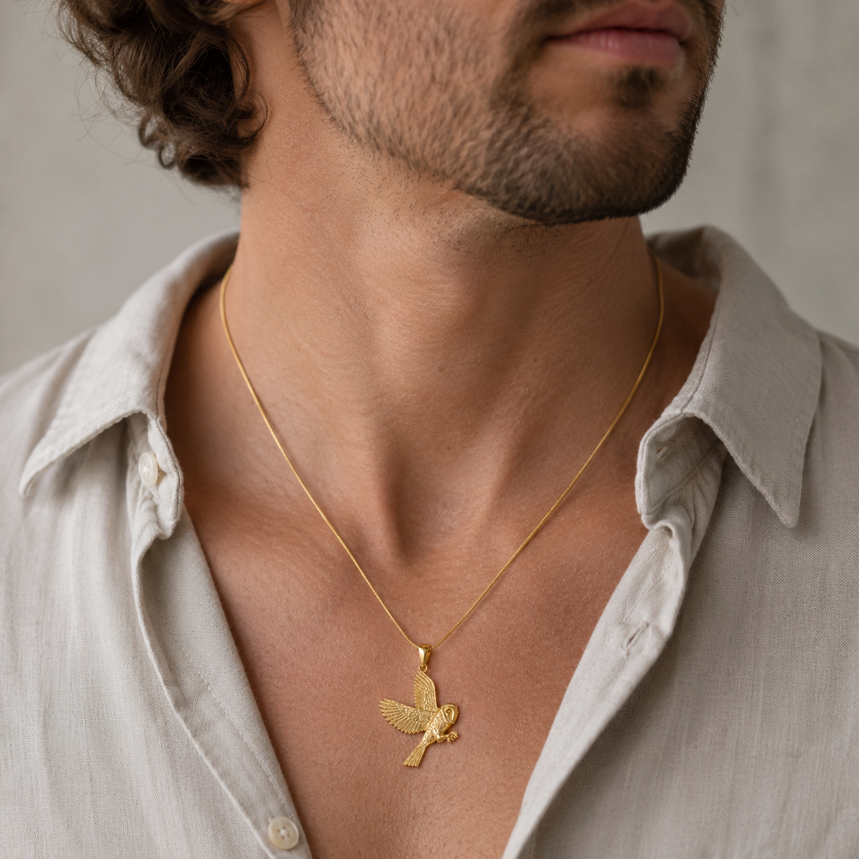 Man wearing a gold barn owl pendant necklace on an 18 inch snake chain From the bird collection at Twelve Sikver Trees Jewellery 