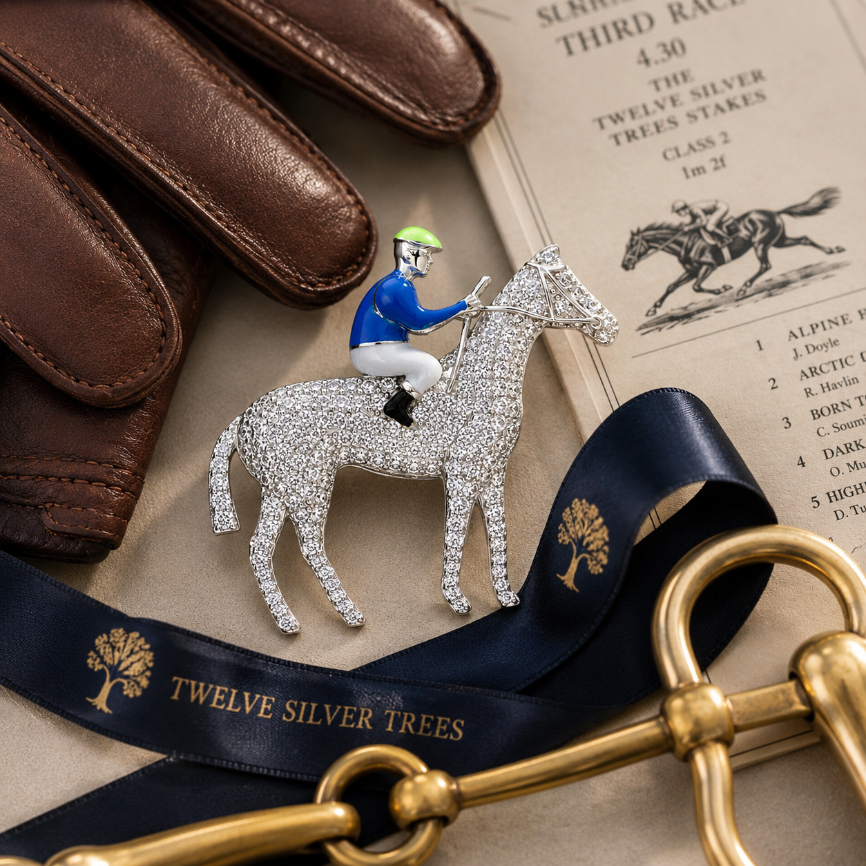Horse and jockey pavé sterling silver brooch styled with leather gloves, race card and brass snaffle in luxury equestrian flat lay