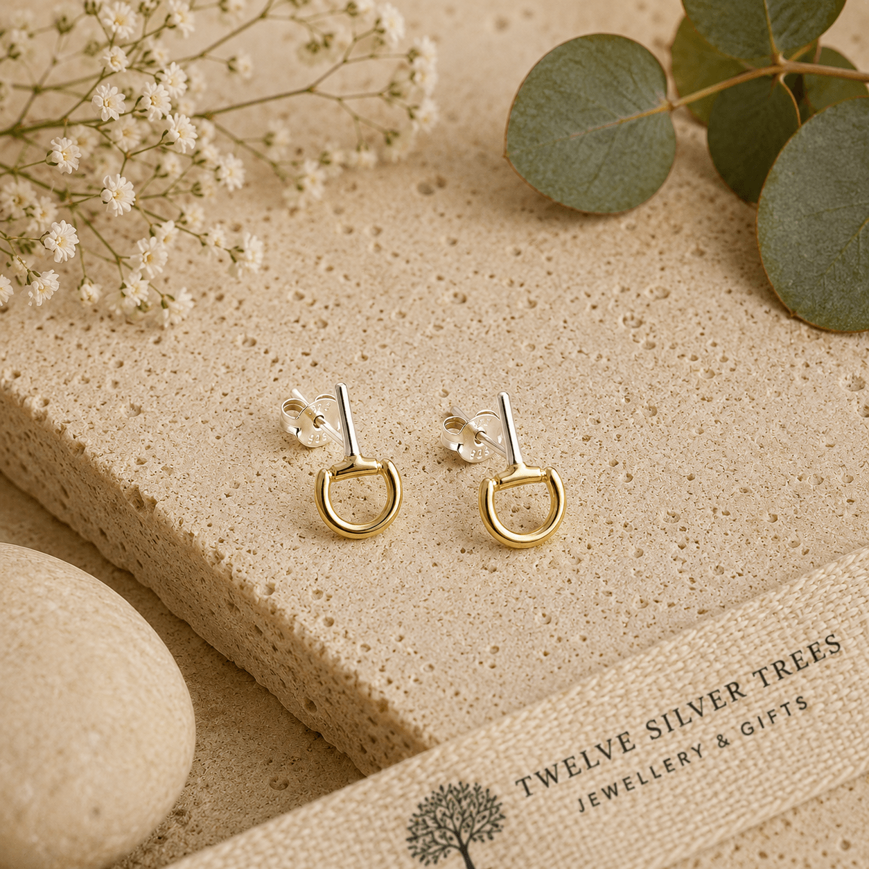 Mini gold vermeil snaffle stud earrings styled on natural stone with botanical details and soft neutral tones