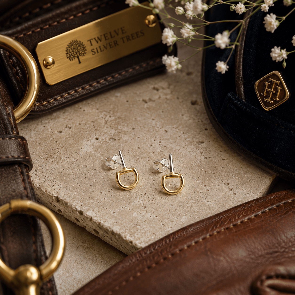 Mini gold vermeil snaffle stud earrings styled with luxury equestrian leather accessories and warm neutral textures