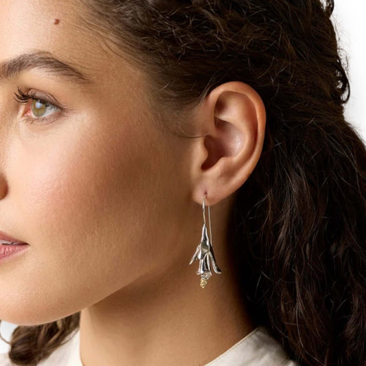 Model wearing statement sterling silver floral drop earrings with gold accents