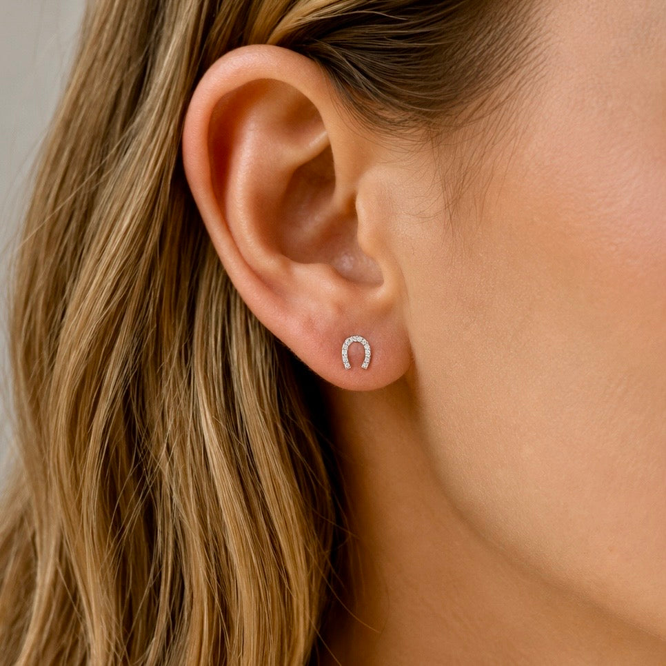  Woman wearing sterling silver horseshoe stud earrings set with cubic zirconia stones