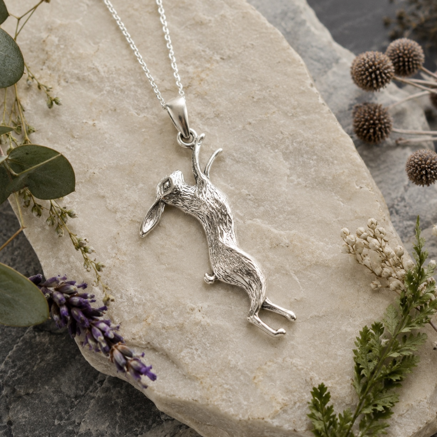Handmade sterling silver March hare pendant necklace styled on natural stone with botanical accents
