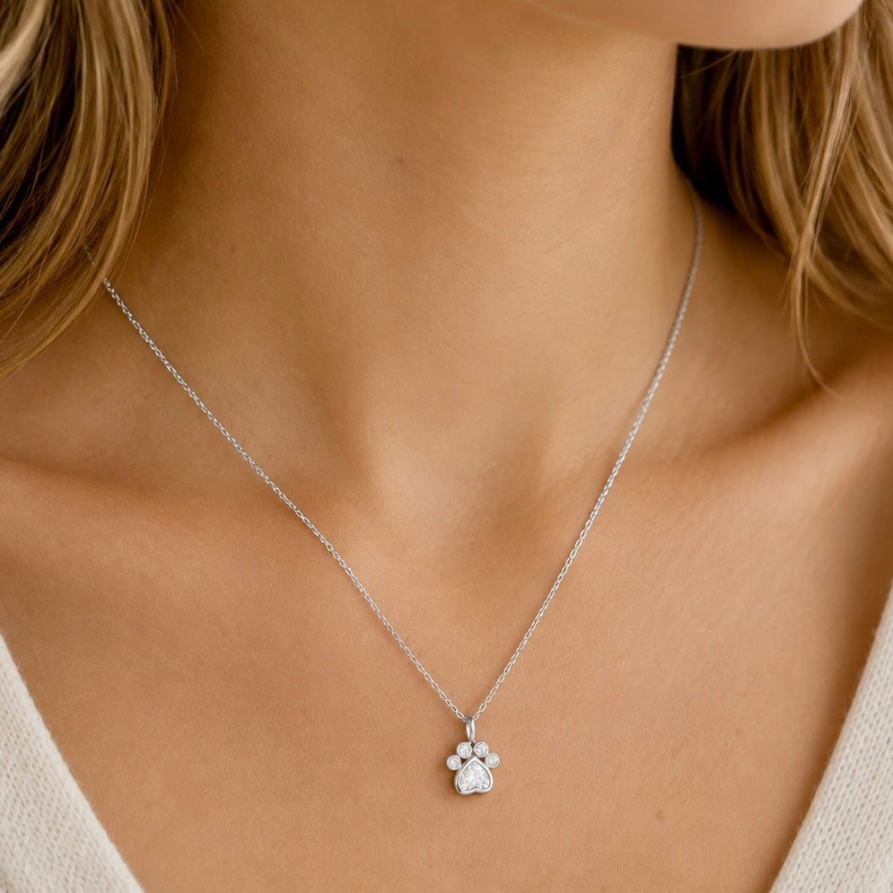 Woman wearing a sterling silver paw print pendant necklace with cubic zirconia stones
