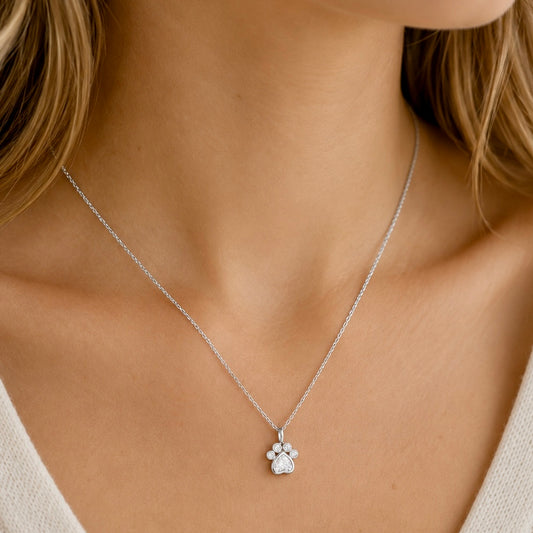 Woman wearing a sterling silver paw print pendant necklace with cubic zirconia stones
