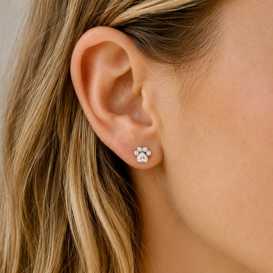 Woman wearing sterling silver paw print stud earrings with cubic zirconia stones