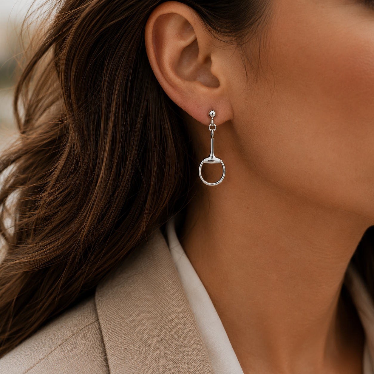 Model wearing sterling silver snaffle drop earrings inspired by classic equestrian tack designs