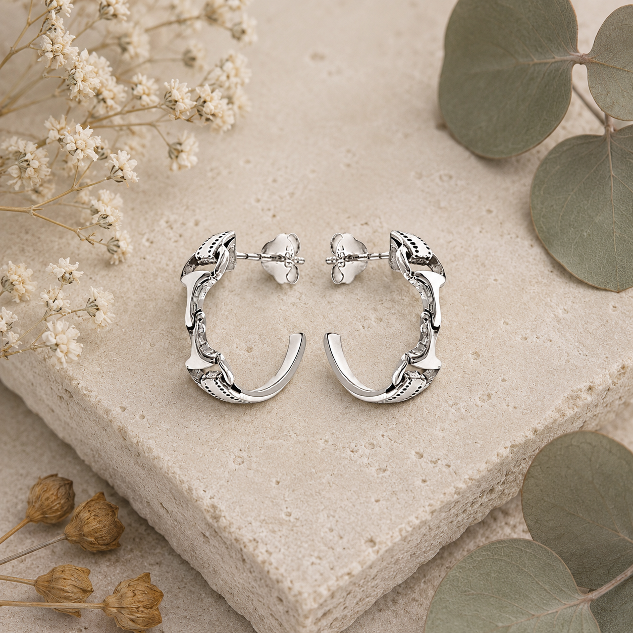 Sterling silver snaffle half hoop earrings styled on stone and botanical background