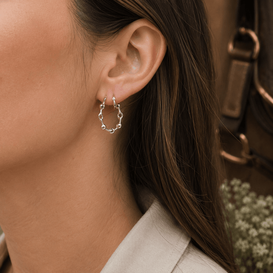 Sterling silver snaffle hoop earrings being worn, showing elegant equestrian-inspired styling and polished silver detail