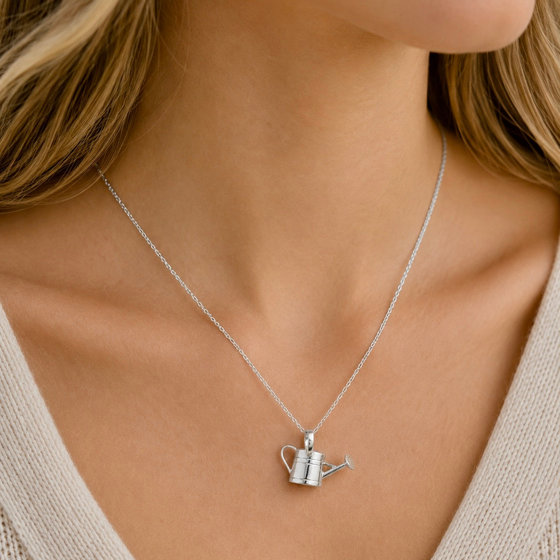 Woman wearing a sterling silver watering can pendant necklace on an adjustable chain.