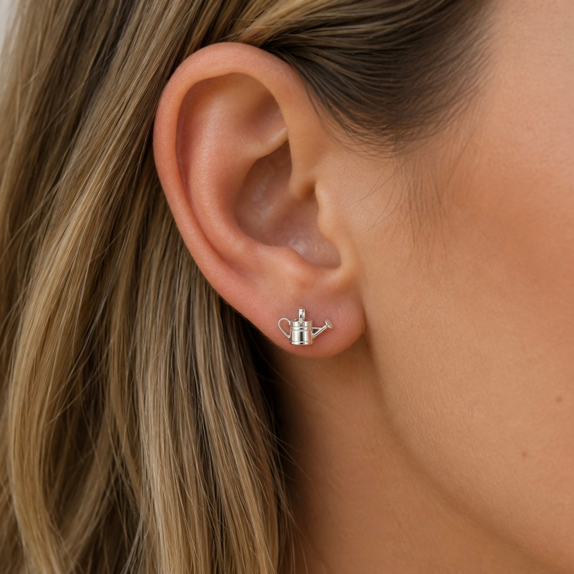 Woman wearing sterling silver watering can stud earrings inspired by gardening and nature.
