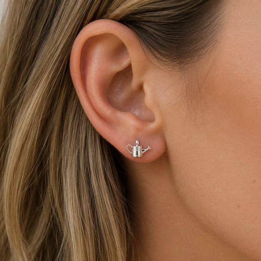 Woman wearing sterling silver watering can stud earrings inspired by gardening and nature.