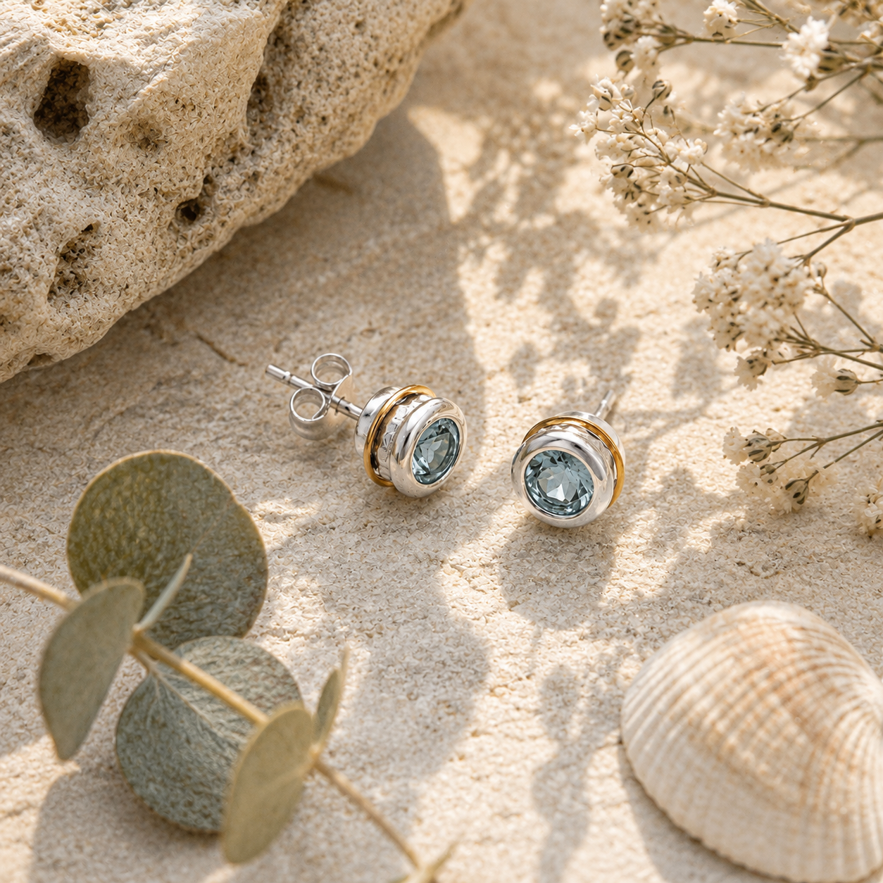 Handcrafted Sky Blue Topaz stud earrings styled with shells, stone and soft natural sunlight